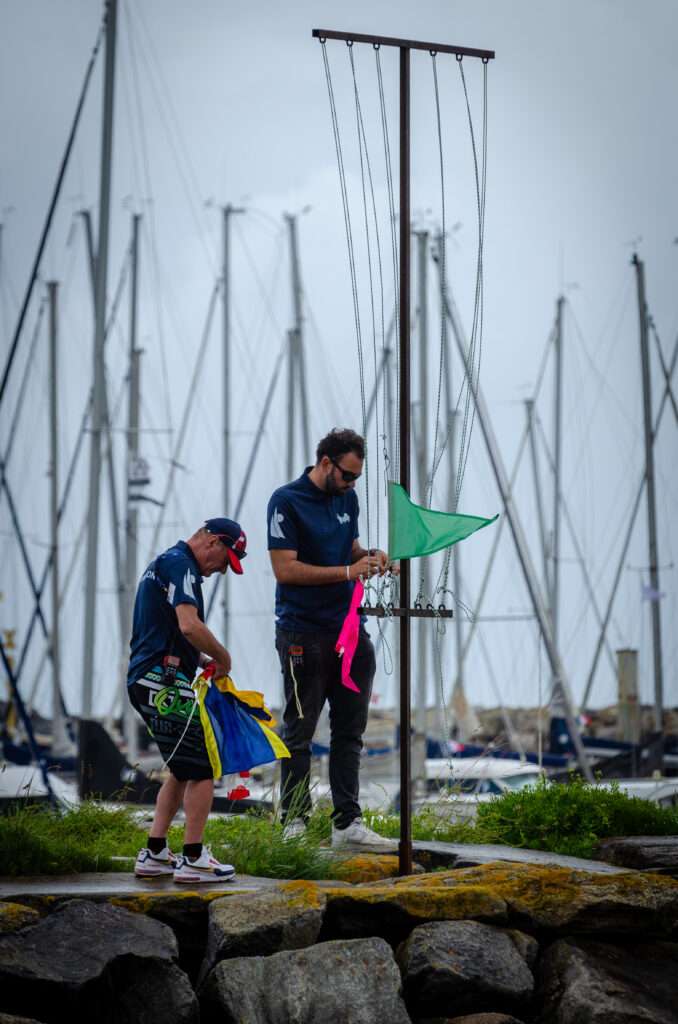 Photo de deux de nos moniteurs mettant en place les pavillons pour la coupe régionale de voile des Pays de la Loire